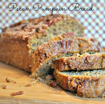 A loaf of pecan and pumpkin bread that has a few slices carved out of it.