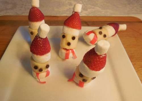 Four Santa treats standing up on a plate, and one that has fallen over.