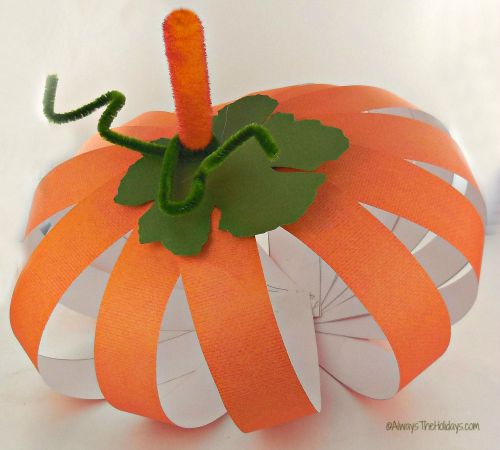 A simple paper pumpkin craft on a white tabletop.
