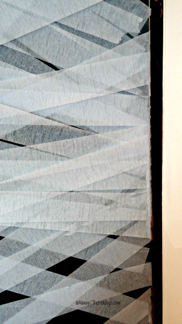 Taping paper streamers around the side of a door.