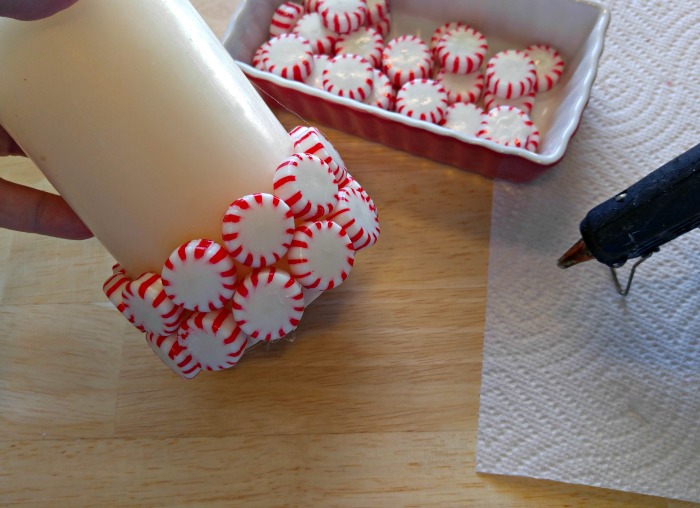 hot gluing peppermints Hot glue the peppermints around the candle, staggering each row slightly.
