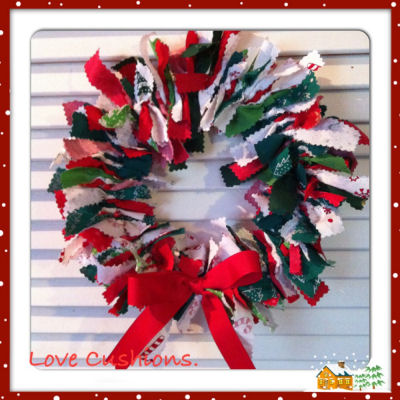 Scrap fabric Christmas wreath hanging on a white wall.