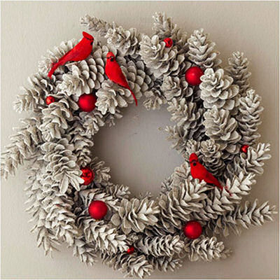 Pine cone wreath dressed up with cardinals and red berries.