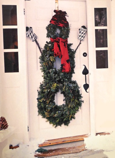 Three wreaths formed into a snowman decoration on a front door.