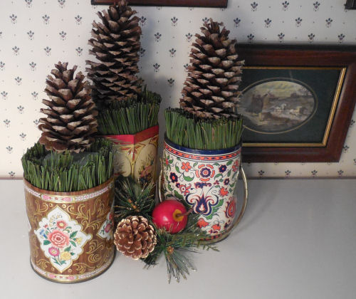 Three DIY pine cone Christmas trees on a ledge against wallpaper.
