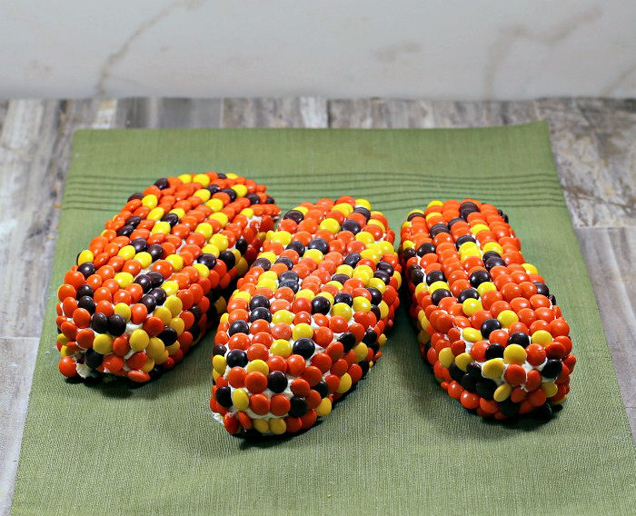 Three Indian corn cakes. Three cake pieces with Reeses pieces on top of frosting.