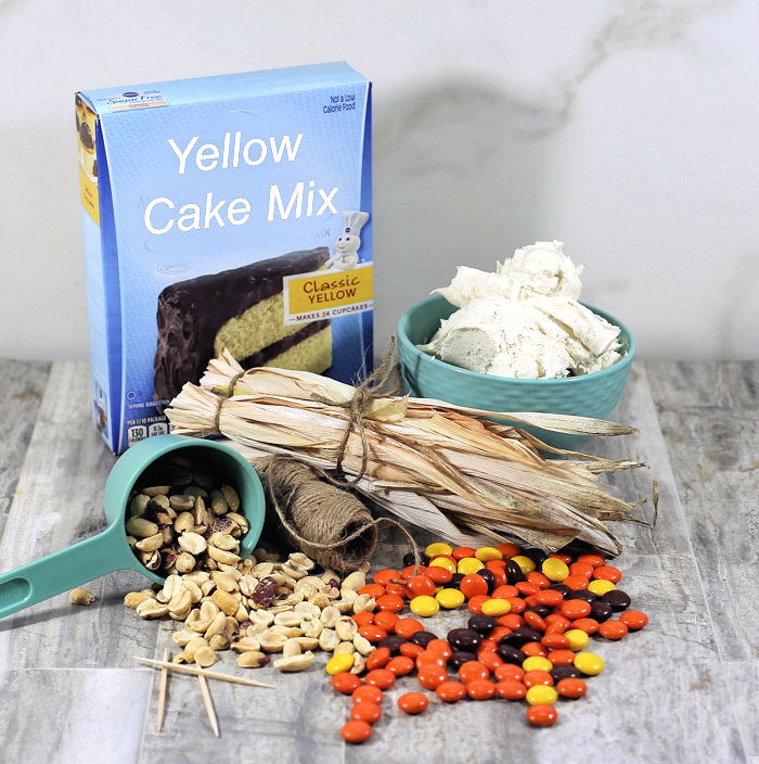 Ingredients for Indian corn cakes. Yellow cake mix, frosting, Reese's pieces, peanuts, frosting, corn stalks, jute and toothpicks.