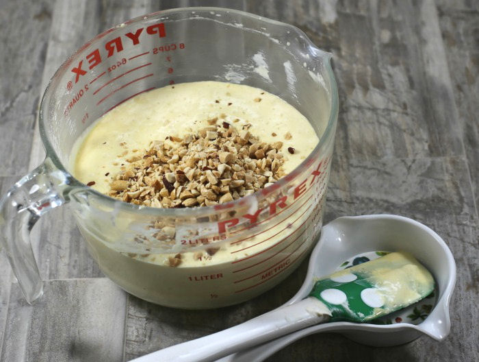Adding peanuts to a yellow cake mix. Peanuts in yellow cake mix with spatula.