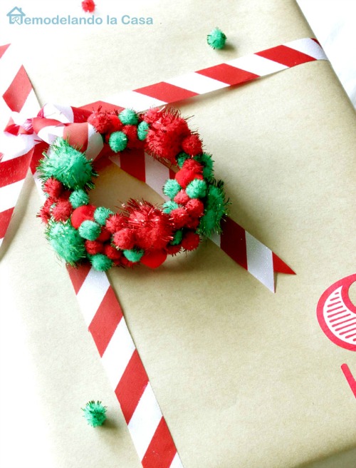 A present wrapped in brown paper with a pom pom package ornament.