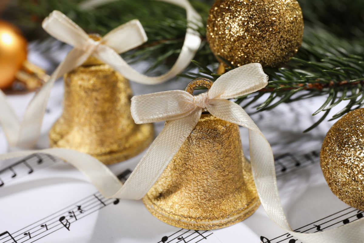 Gold bells sitting on some sheet music.