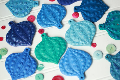 Blue and green polymer Clay gift wrap ornaments on a white table.