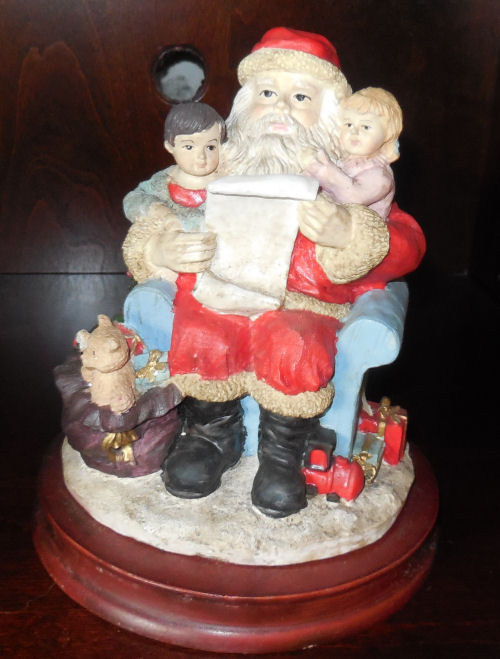 Reading Santa. Reading Santa who has two children gathered around him as he reads a list off a scroll of paper.