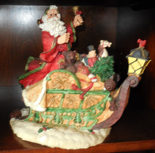 Santa in sleigh holding a bell.