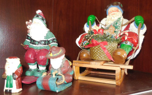 Five snow loving Santas on sleds.