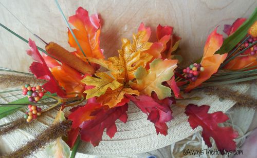 Fall floral picks attached to the folded brim of a straw hat.