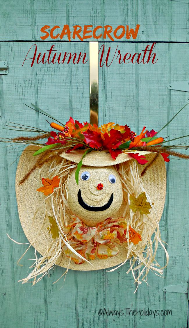 Learn How to Make a Straw Hat Scarecrow Wreath An adorable straw hat scarecrow wreath door decoration hanging on a gold wreath hanger on a teal door with text that reads scarecrow autumn wreath in orange text above it.