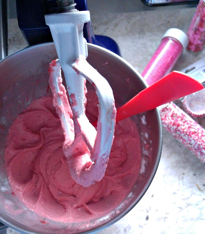 A progress photo of a cheesecake mixture for raspberry cheesecake truffles in a mixing bowl.