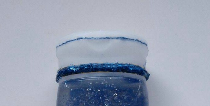 Calm down jar with a lid sealed with blue glitter glue.