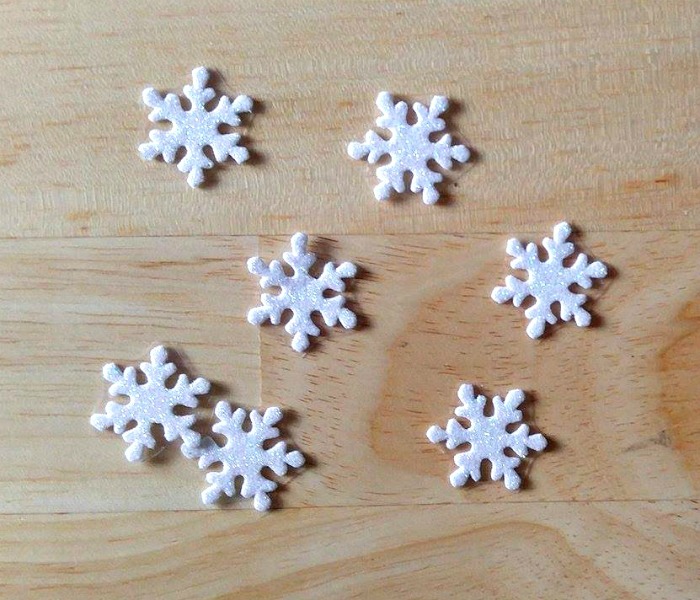 White Snowflake stickers on a wood board.
