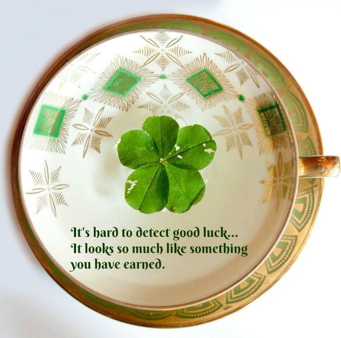 Teacup with a St. Patrick's Day quote overlay. A St Patrick's day quotes about luck text overlay on top of a teacup with a four leaf clover.