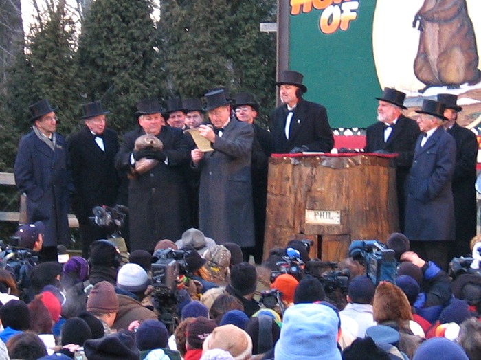 men in black hats with a groundhog on a stage Groundhog day in Pennsylvania
