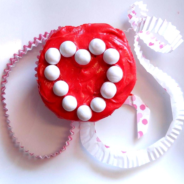 White sixlets make a heart shape on this Valentine Cupcake