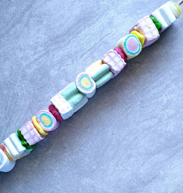 Marshmallow skewer. A marshmallow skewer featuring colorful assorted marshmallows on a grey slate table.
