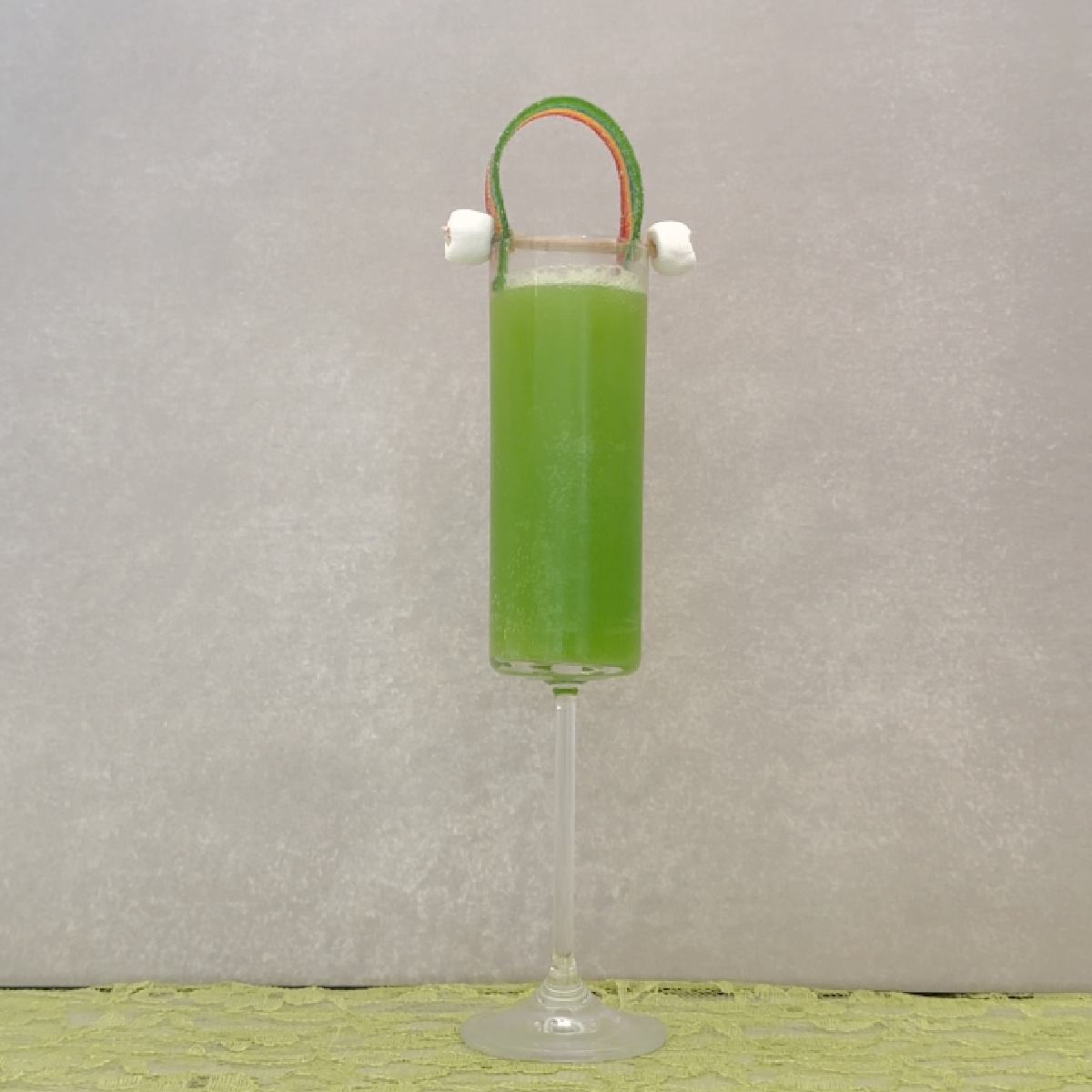 Green mimosa for St. Patrick's Day A St. Patrick's Day mimosa in a champagne flute, which is garnished with a rainbow made of two marshmallows and a sour belt, sitting on top of this green mimosa.
