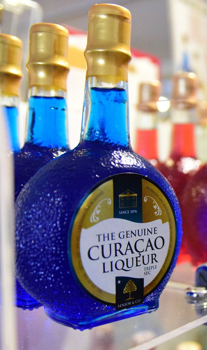 A blue Curacao bottle. A bottle of blue Curacao liqueur on a glass shelf.
