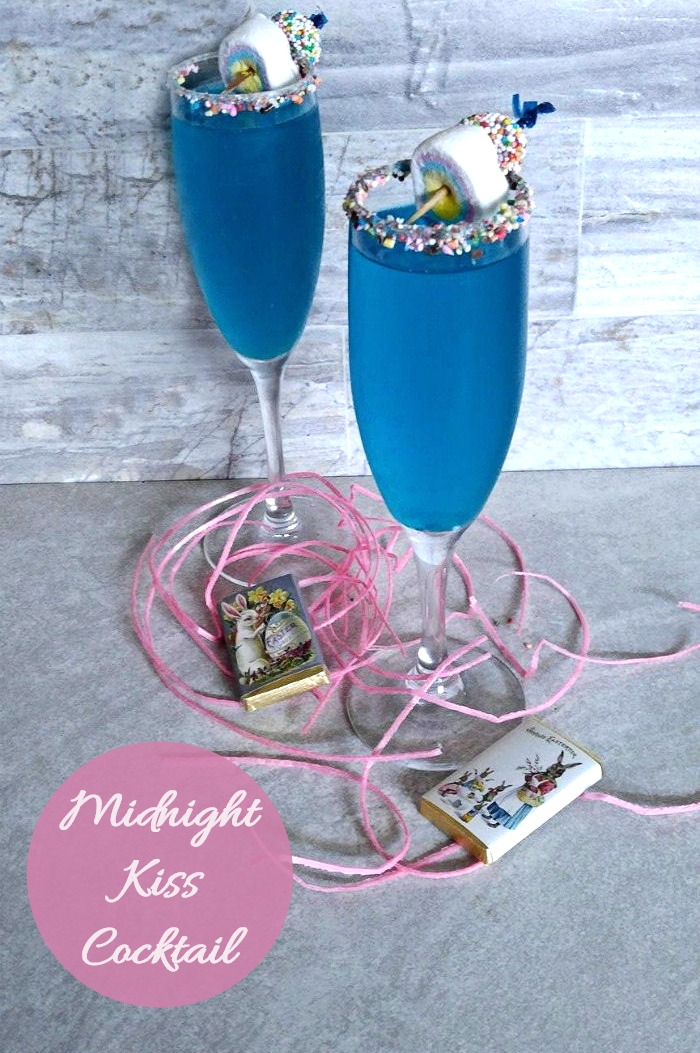 Two blue cocktails for Easter. A blue cocktail for Easter with a candy garnish on a counter with a text overlay reading "Easter Midnight Kiss Cocktail".