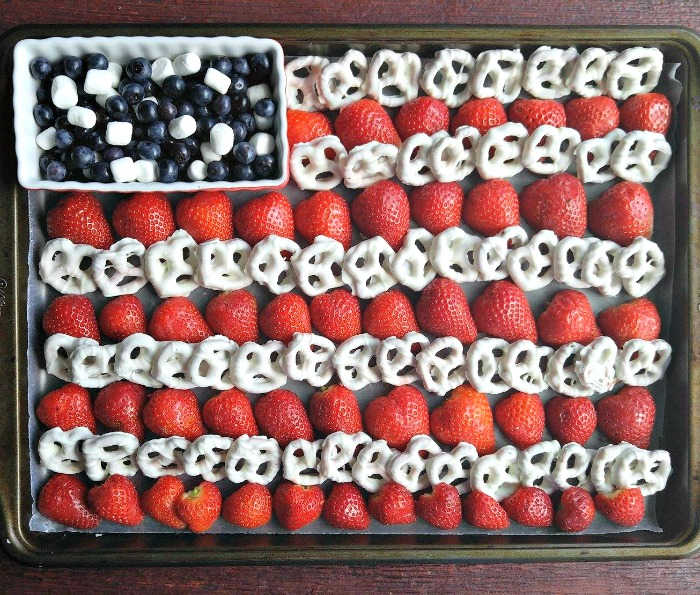 Fruit platter for the fourth of july American flag made out of blueberries, strawberries, mini marshmallows and yogurt pretzels.