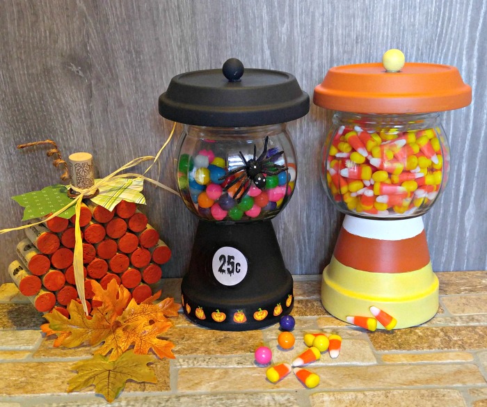 Halloween display of easy crafts. Halloween DIY bubblegum machine and DIY gumball candy jar made from clay pots near a wine cork pumpkin, fall leaves, gum and candy corn.