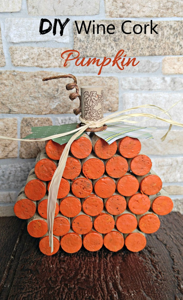 One wine cork pumpkin craft on a wooden tabletop with a text overlay that says DIY wine cork pumpkin above it.