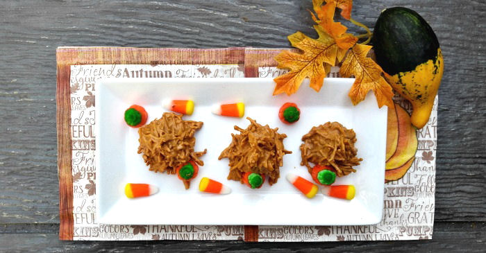 Pumpkin haystack cookies Three pumpkin haystack cookies on a plate garnished with candy corn and candy pumpkins, all sitting on a fall napkin with artificial leaves and a gourd beside it.