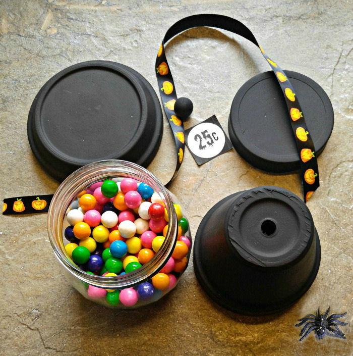 Supplies for the project Materials for the Halloween gumball machine DIY craft - painted clay pots, sticker, Halloween ribbon, and glass bowl filled with bubblegum.