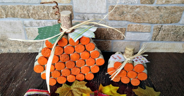Two DIY wine cork pumpkins against a stone wall.