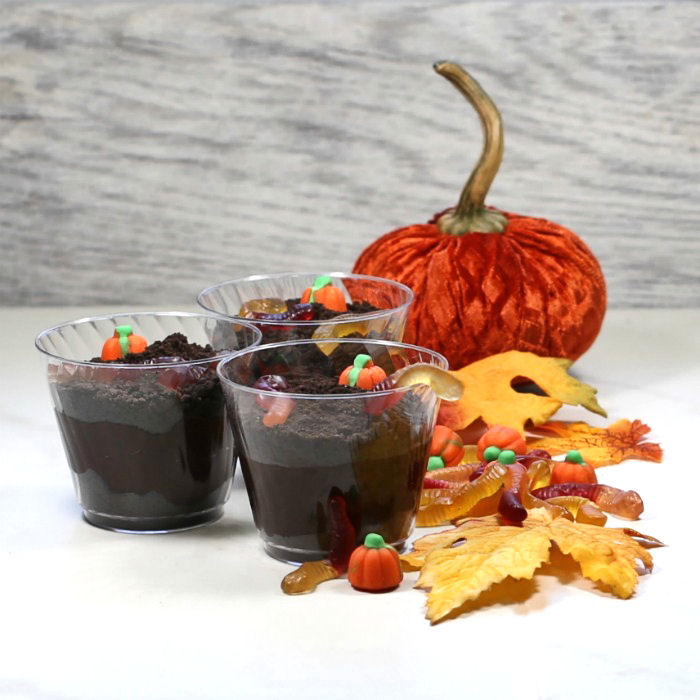 Dirt pudding dessert cups with leaves, worms and pumpkins.