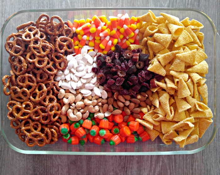 Glass bowl with pretzels, candy corn and pumpkins, Bugles snacks, nuts, pumpkin seeds and dried fruit.