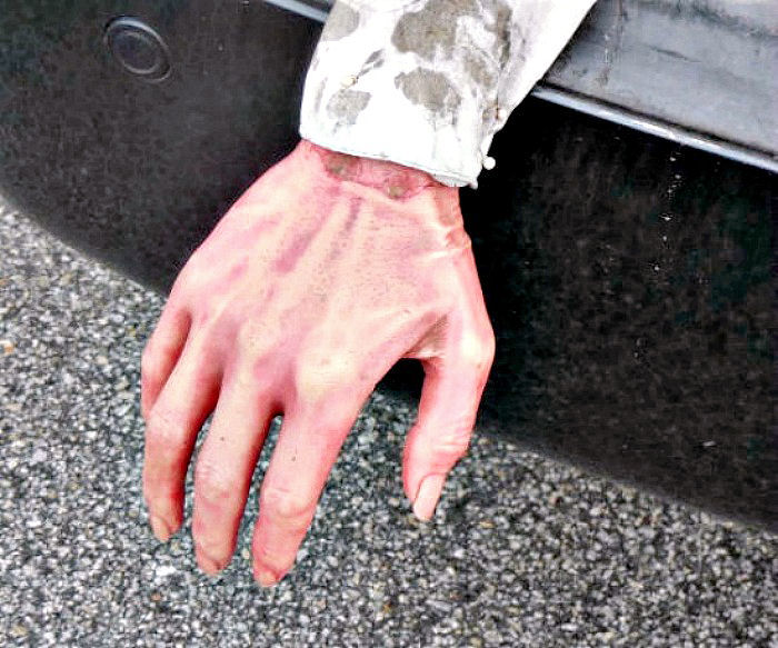 Fake hand sticking out the back of a car trunk.