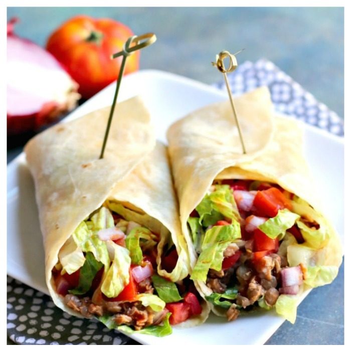 Healthy burrito on plate. A veggie based burrito cut in half on a square white plate.