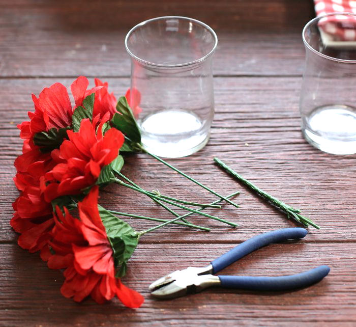cutting silk flowers with wire cutters Sprigs of red silk flowers with wire cutters beside them.