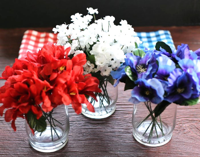 red white and blue silk flowers in glasses Glasses with red white and blue flowers in them, to make a patriotic table decoration.