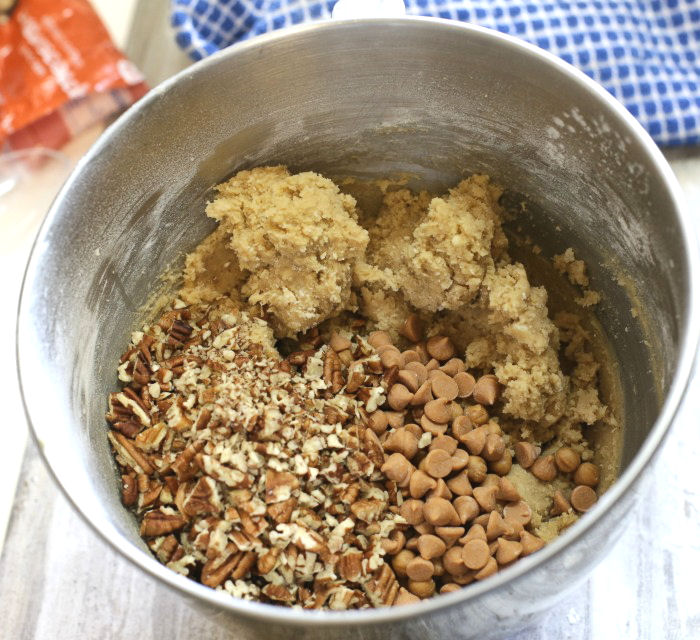 Butterscotch brownie ingredients in a bowl. Nuts, butterscotch chips and brown sugar batter in a stainless steel bowl.