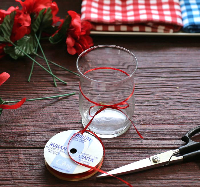 glass with a red ribbon bow A red ribbon tied around the middle of the glass, to make Independence Day decorations.