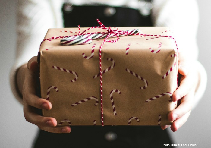 Package with candy cane stickers. Gift holding package wrapped in butcher paper, kitchen twine and candy cane stickers.