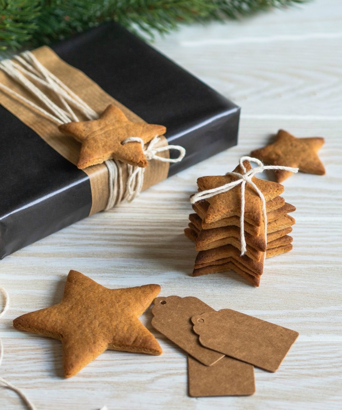 Christmas cookies tied on a gift. Christmas cookies on a blue gray Christmas gift and paper tags.