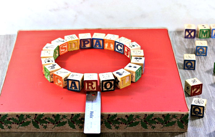 Measuring the blocks. Ruler, alphabet blocks on Christmas base.