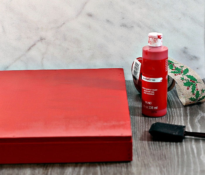 Wood base painted red. Wood base painted with red acrylic paint and bottle of paint and foam brush.