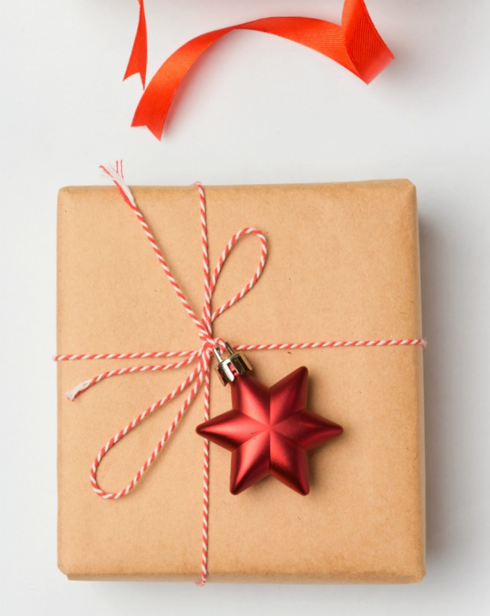 Star ornament on a wrapped present Christmas wrapping idea with butcher paper,. kitchen string and star ornament.