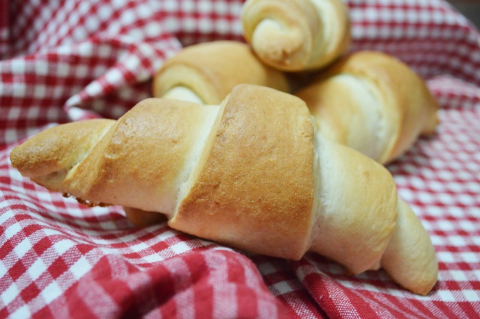 Four crescent rolls. Four crescent rolls arranged on a red and white checked picnic basket liner.